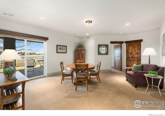 dining space with baseboards, visible vents, and light carpet