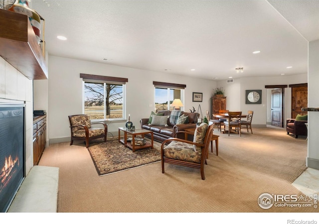 living room with visible vents, baseboards, a lit fireplace, light carpet, and recessed lighting