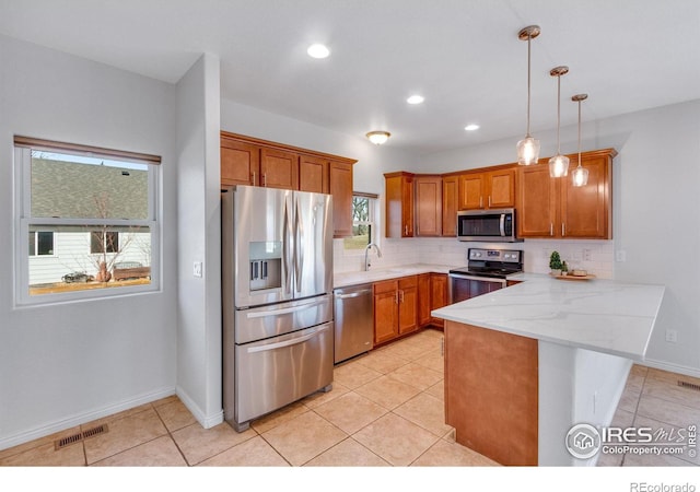 229 3rd St, Fort Collins, CO 80524 - kitchen with appliances with stainless steel finishes, a peninsula, brown cabinetry, decorative backsplash, and decorative light fixtures
