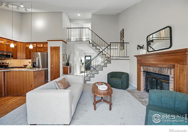 living room with stairway, baseboards, a high ceiling, and a fireplace