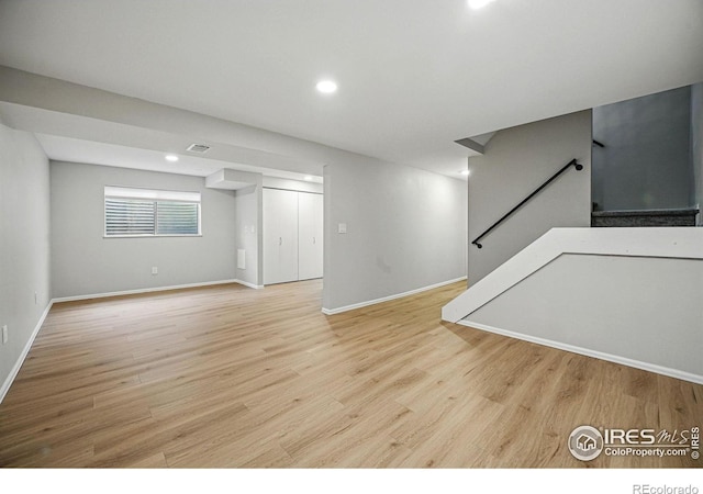 below grade area featuring visible vents, wood finished floors, recessed lighting, stairway, and baseboards