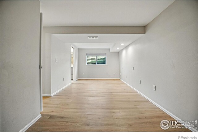 hallway with visible vents, light wood-type flooring, and baseboards