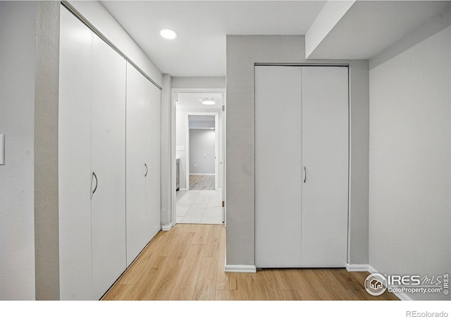 bedroom with baseboards, light wood-style floors, and multiple closets