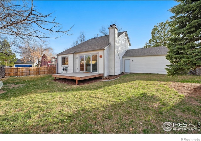 back of property featuring a chimney, fence, a lawn, and a wooden deck