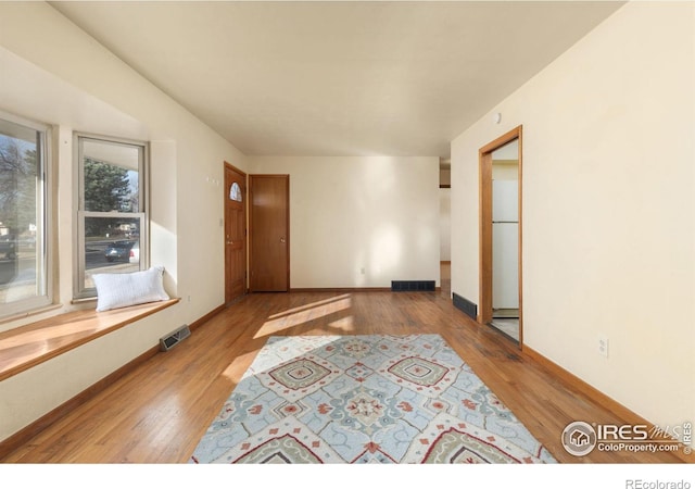 spare room featuring wood finished floors, visible vents, and baseboards