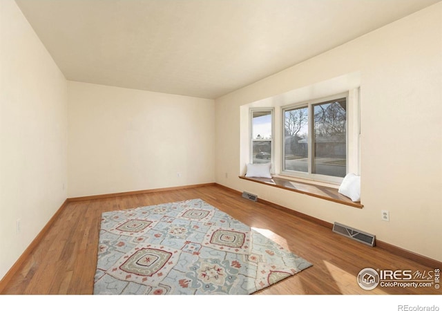 empty room with visible vents, baseboards, and wood finished floors