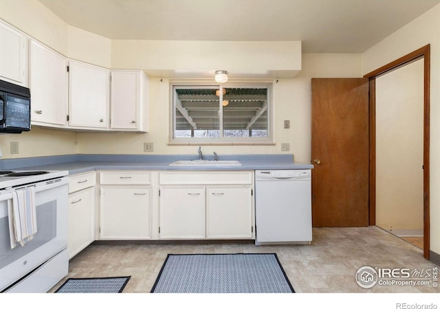 kitchen with a sink, white appliances, white cabinets, and light countertops