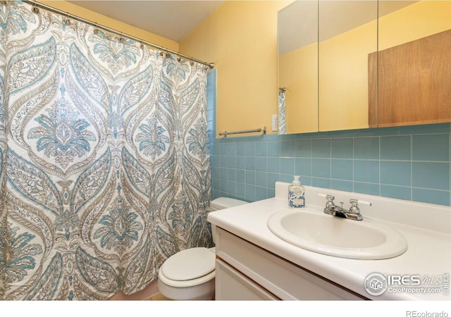 bathroom with toilet, curtained shower, tile walls, and vanity