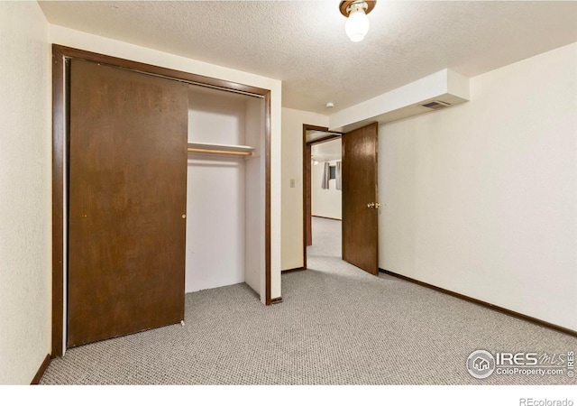 unfurnished bedroom with a textured ceiling, visible vents, a closet, and light carpet