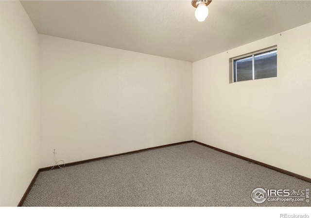 carpeted empty room with baseboards and a textured ceiling