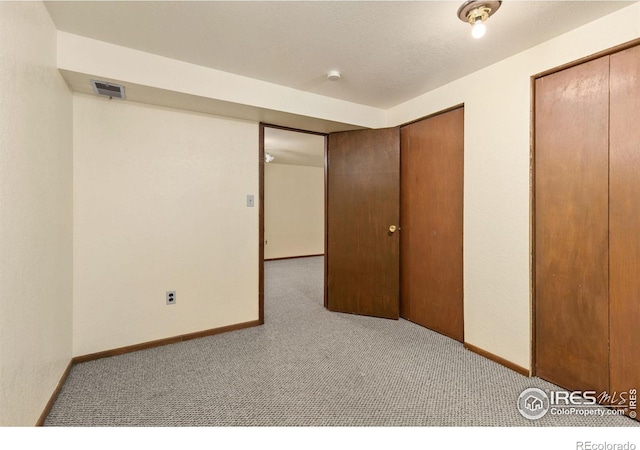 unfurnished bedroom featuring carpet flooring, baseboards, visible vents, and two closets