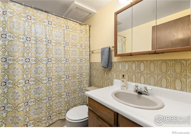 full bathroom featuring a wainscoted wall, a shower with curtain, toilet, tile walls, and vanity