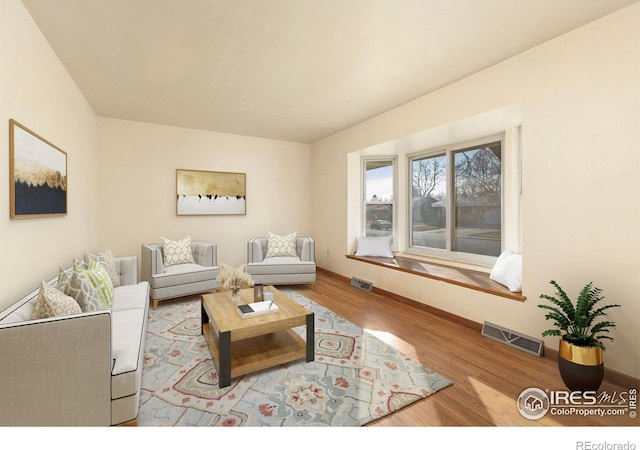 living area featuring visible vents, baseboards, and wood finished floors