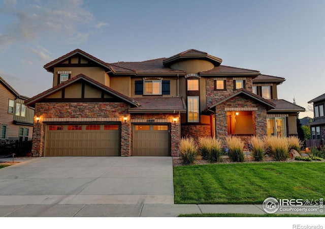 view of front facade with a front lawn, stone siding, driveway, and stucco siding