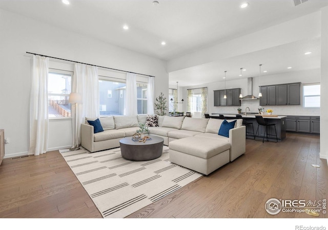 living area featuring recessed lighting, baseboards, and light wood-style flooring