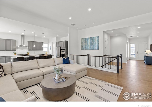 living room featuring light wood-style flooring, recessed lighting, and visible vents