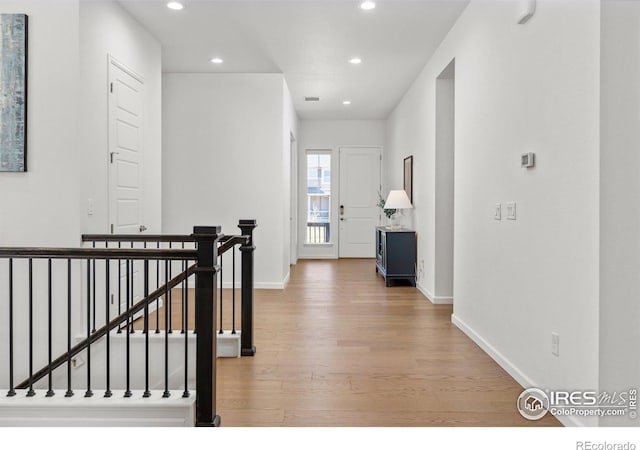 hallway featuring recessed lighting, baseboards, an upstairs landing, and light wood finished floors