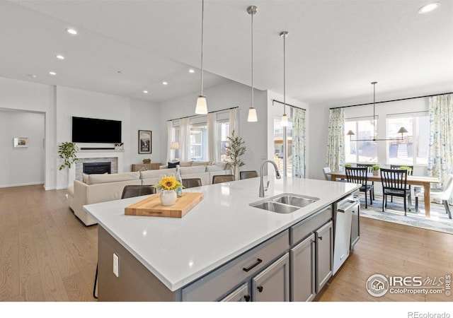 kitchen featuring gray cabinetry, a sink, stainless steel dishwasher, recessed lighting, and light wood finished floors