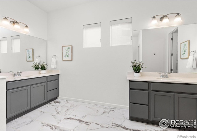 bathroom with a sink, baseboards, two vanities, and marble finish floor