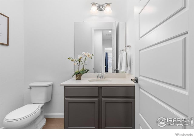 bathroom with toilet, vanity, and baseboards