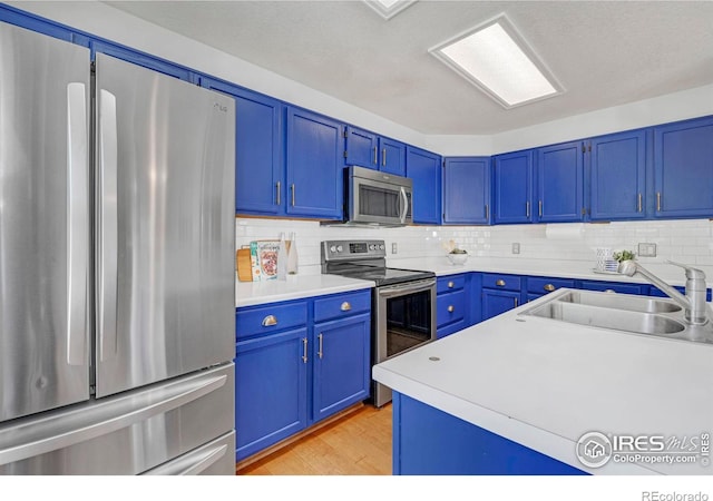 kitchen with blue cabinetry, appliances with stainless steel finishes, and a sink