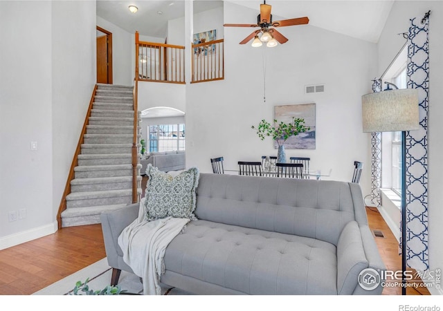 living area featuring visible vents, stairway, a ceiling fan, and wood finished floors