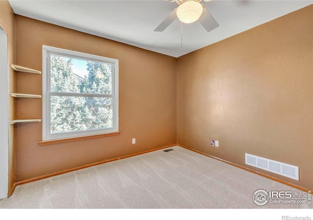 carpeted empty room with visible vents, baseboards, and ceiling fan