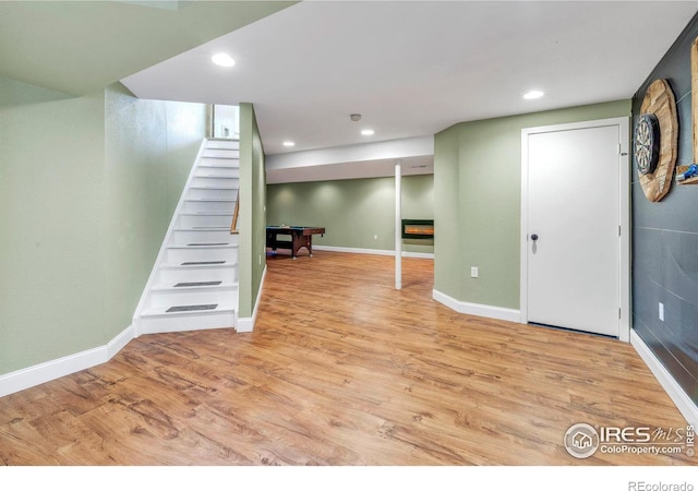 finished basement featuring stairs, recessed lighting, light wood-style floors, and baseboards