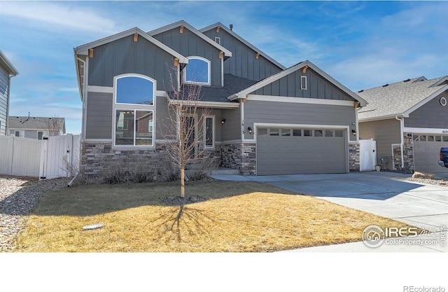 craftsman house featuring fence, concrete driveway, a garage, stone siding, and board and batten siding