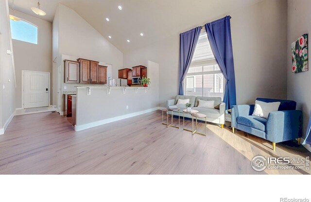 living area featuring a wealth of natural light, high vaulted ceiling, and light wood-style floors