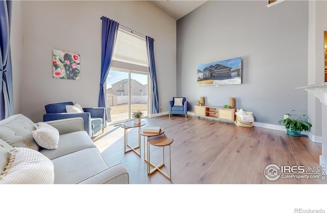 living area with wood finished floors, baseboards, and a towering ceiling