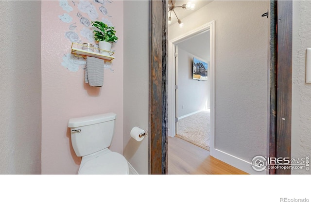 bathroom featuring toilet, baseboards, and wood finished floors