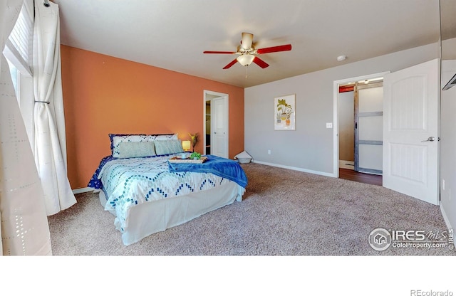 bedroom featuring ceiling fan, baseboards, a barn door, and carpet floors