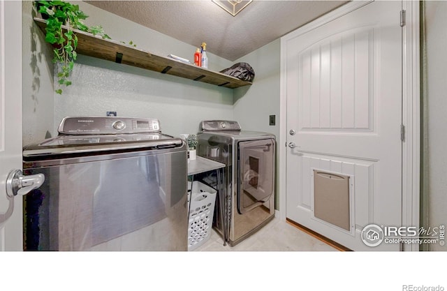 laundry area with laundry area, light tile patterned flooring, independent washer and dryer, and a textured ceiling