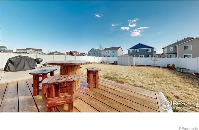 wooden deck with a residential view, a shed, a yard, a fenced backyard, and an outbuilding