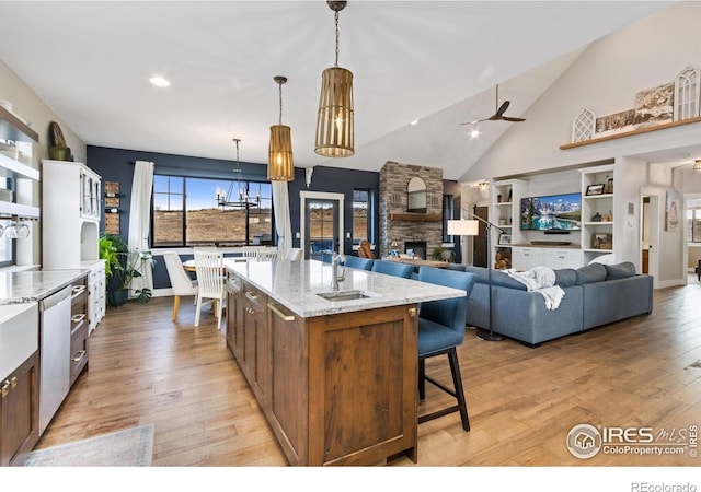 4528 Del Colina Way, Laporte, CO 80535 - kitchen with light wood-type flooring, a kitchen bar, a chandelier, a fireplace, and light stone counters
