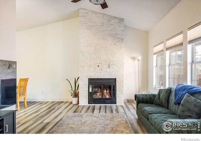 living area featuring wood finished floors, a fireplace, baseboards, and ceiling fan