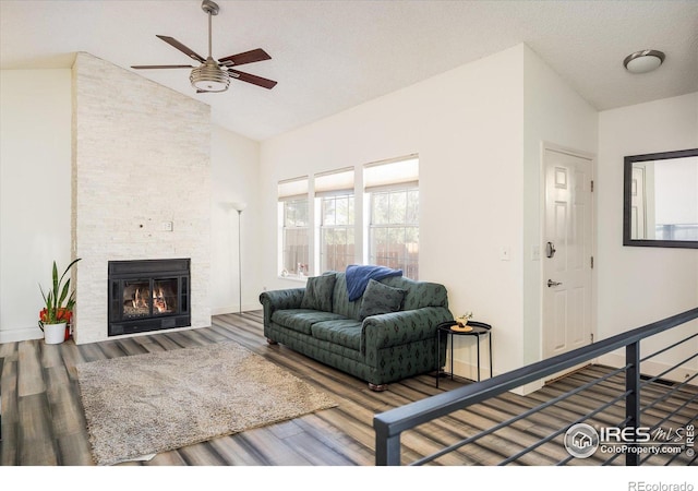 living area with baseboards, wood finished floors, a fireplace, and a ceiling fan