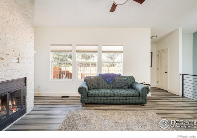 living area featuring a healthy amount of sunlight, a fireplace, a ceiling fan, and wood finished floors