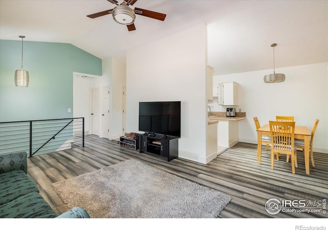 living room featuring lofted ceiling, light wood-style floors, baseboards, and ceiling fan