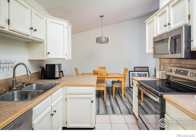 kitchen featuring light tile patterned floors, a sink, white cabinets, appliances with stainless steel finishes, and backsplash