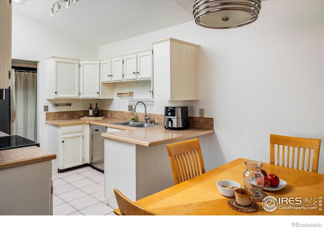 kitchen featuring a sink, a peninsula, white cabinets, light tile patterned floors, and dishwasher