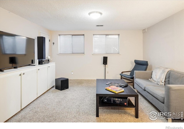 living area with visible vents, baseboards, carpet, and a textured ceiling