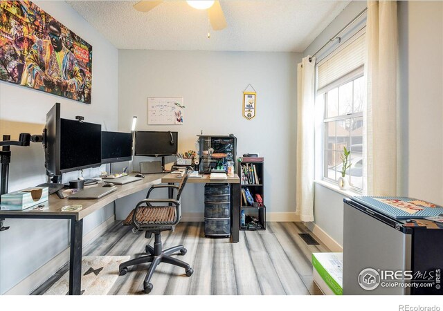 office featuring wood finished floors, baseboards, visible vents, ceiling fan, and a textured ceiling