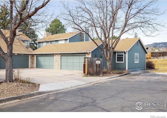 view of front of property featuring driveway, a shingled roof, a garage, and fence