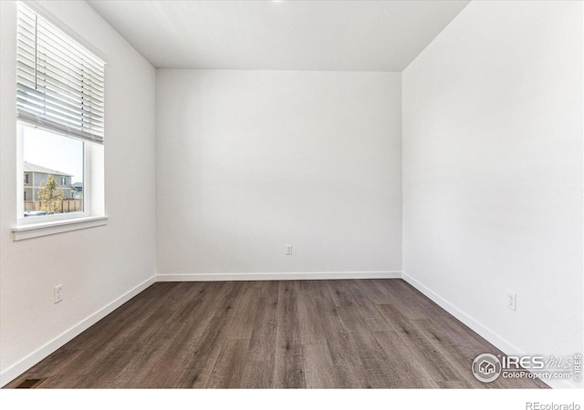 unfurnished room with baseboards and dark wood-style flooring