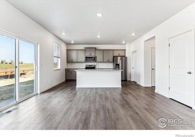 kitchen with stainless steel appliances, tasteful backsplash, gray cabinetry, and wood finished floors