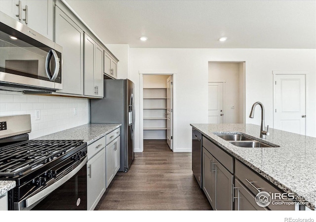 kitchen featuring dark wood finished floors, a sink, decorative backsplash, gray cabinetry, and stainless steel appliances