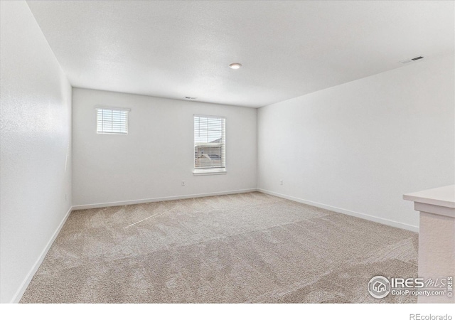 unfurnished room featuring visible vents, baseboards, and carpet