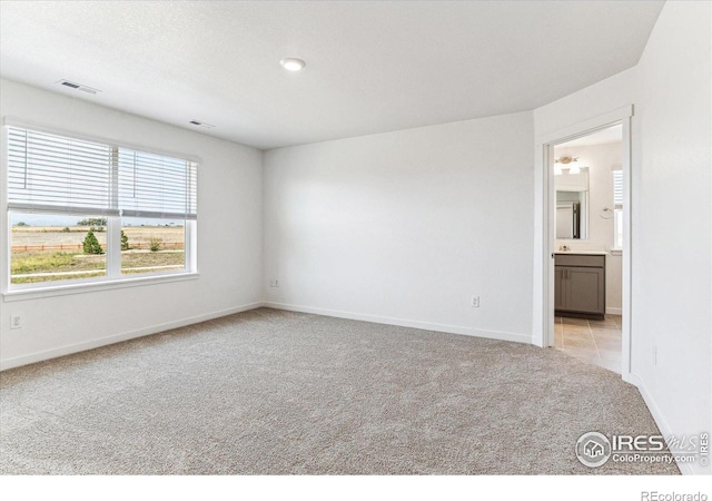 unfurnished room with visible vents, baseboards, and light colored carpet